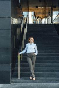 Confident businesswoman with hand in pocket on staircase