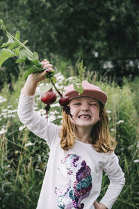 Innocent blond girl with beetroots standing in vegetable garden