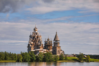 View of building by river against cloudy sky