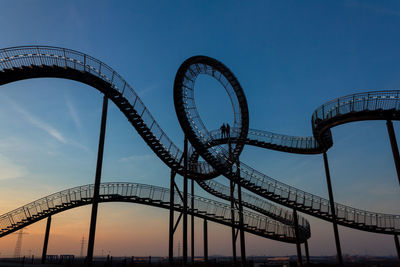 Low angle view of rollercoaster against blue sky