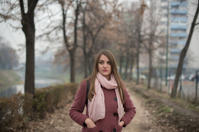 Portrait of young woman standing against bare trees