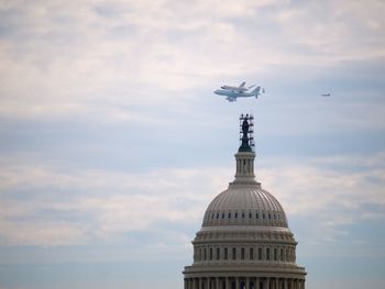 Airplanes flying against sky with church in foreground