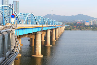 Bridge over river in city against sky