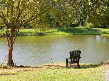 Chair by lake against trees