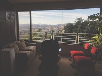 Chairs and table by window against sky