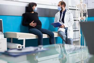 Doctor wearing mask examining patient in clinic