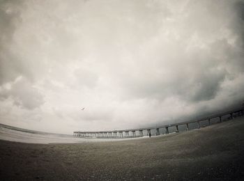 Fish-eye lens of pier over sea against cloudy sky