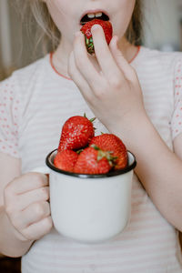 Midsection of woman holding strawberry