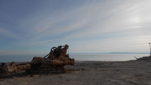 Abandoned crane on beach against sky