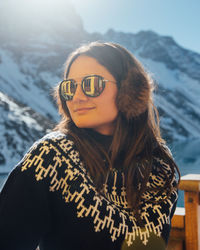 A woman warms up in the sunshine by the mountains in chile.