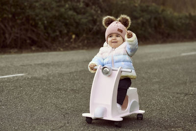 A 1 year old baby girl is with a pink motorcycle outside