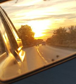 Cars on road against sky during sunset