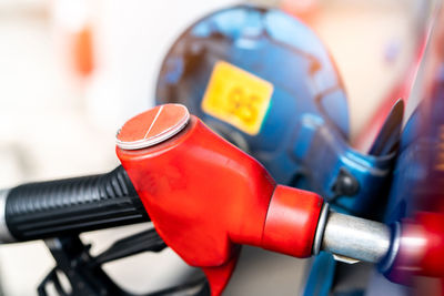 Close-up red fuel nozzle. gasoline pump nozzle. car fueling at gas station. refuel fill up 