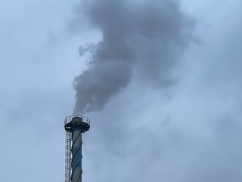 Low angle view of smoke emitting from chimney against sky