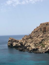 Rock formations by sea against sky