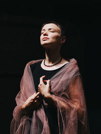 Young woman standing against black background