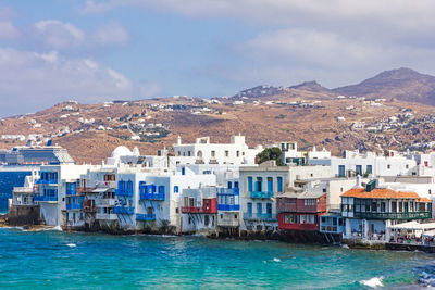 Buildings by sea against sky