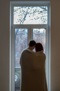 Rear view of woman looking through window