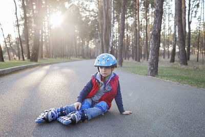 Full length of boy fell on road against trees