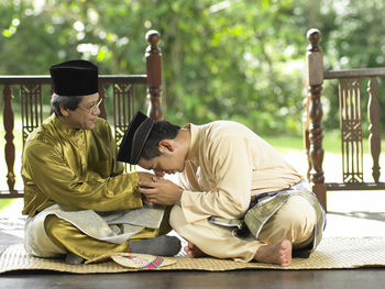 Father and son holding hands while sitting in gazebo in yard