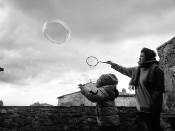 Low angle view of people at bubbles against sky