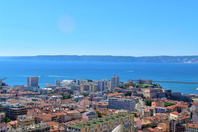 High angle view of city buildings against blue sky