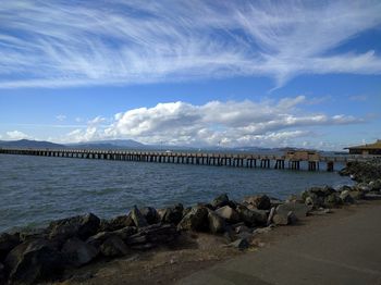 Pier on sea against cloudy sky