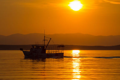 Trawler in the glow of the setting sun. a silhouette off croatia's coast.