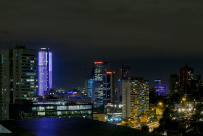 Illuminated buildings in city against sky at night