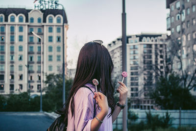 Portrait of woman standing against buildings in city