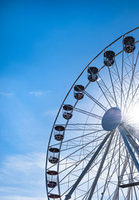 Low angle view of ferris wheel against blue sky