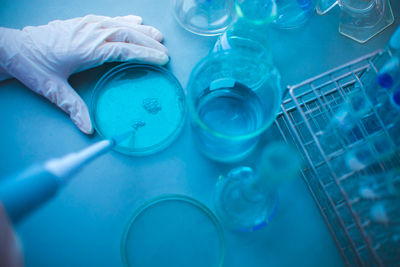 Cropped image of scientist experimenting blue chemical in laboratory
