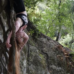 Rear view of smiling young woman by tree in forest