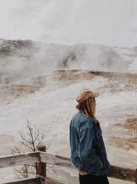 Rear view of woman standing against waterfall