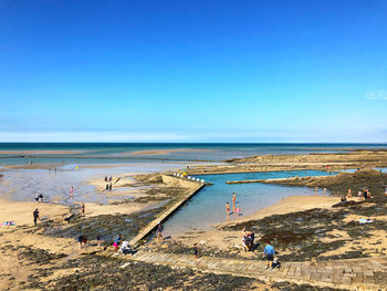 People on beach against clear sky