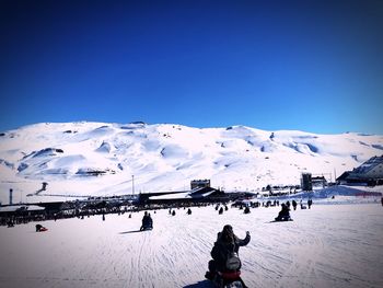 People on snowcapped mountains against clear blue sky