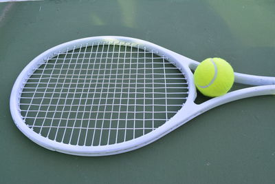 High angle view of ball and tennis racket at sports court