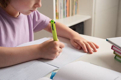 Close-up of children's hands. left-hander writes in a notebook on the table. left handed child. 