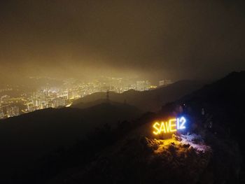 Illuminated street light on silhouette mountain against sky at night