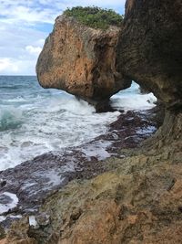 Rock formation on beach against sky