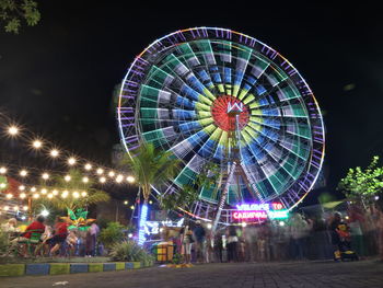 Low angle view of illuminated ferris wheel against sky at night