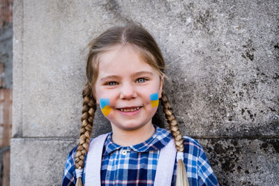 Portrait of young woman standing against wall