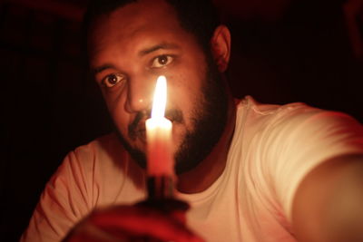 Close-up portrait of young man holding lit candle