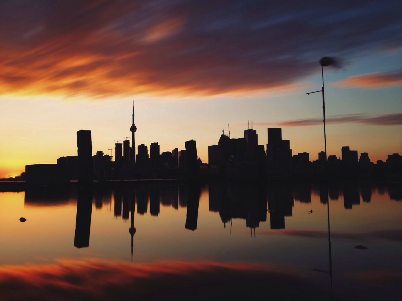 sunset, reflection, water, architecture, silhouette, building exterior, sky, built structure, waterfront, city, cloud - sky, orange color, cloud, river, lake, scenics, dusk, cityscape, skyline, skyscraper