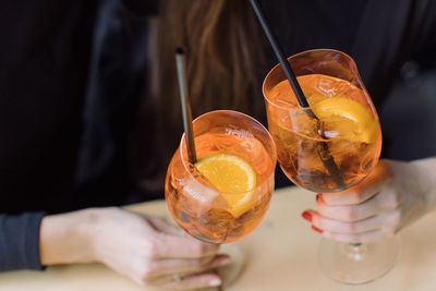 Midsection of women toasting drink glasses