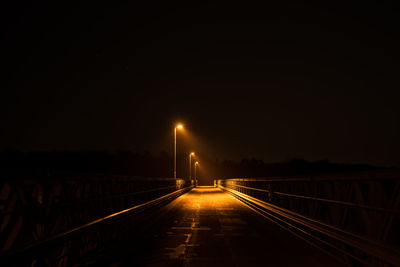 Illuminated empty bridge against sky at night