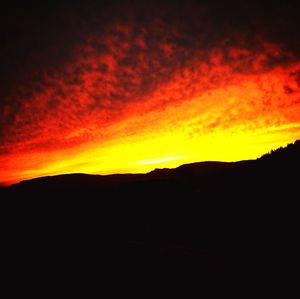 Silhouette landscape against dramatic sky during sunset