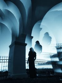 Rear view of silhouette man standing in city against sky