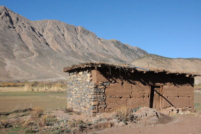 Abandoned building by mountains against clear blue sky
