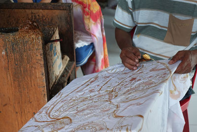 Midsection of man making pattern on textile 